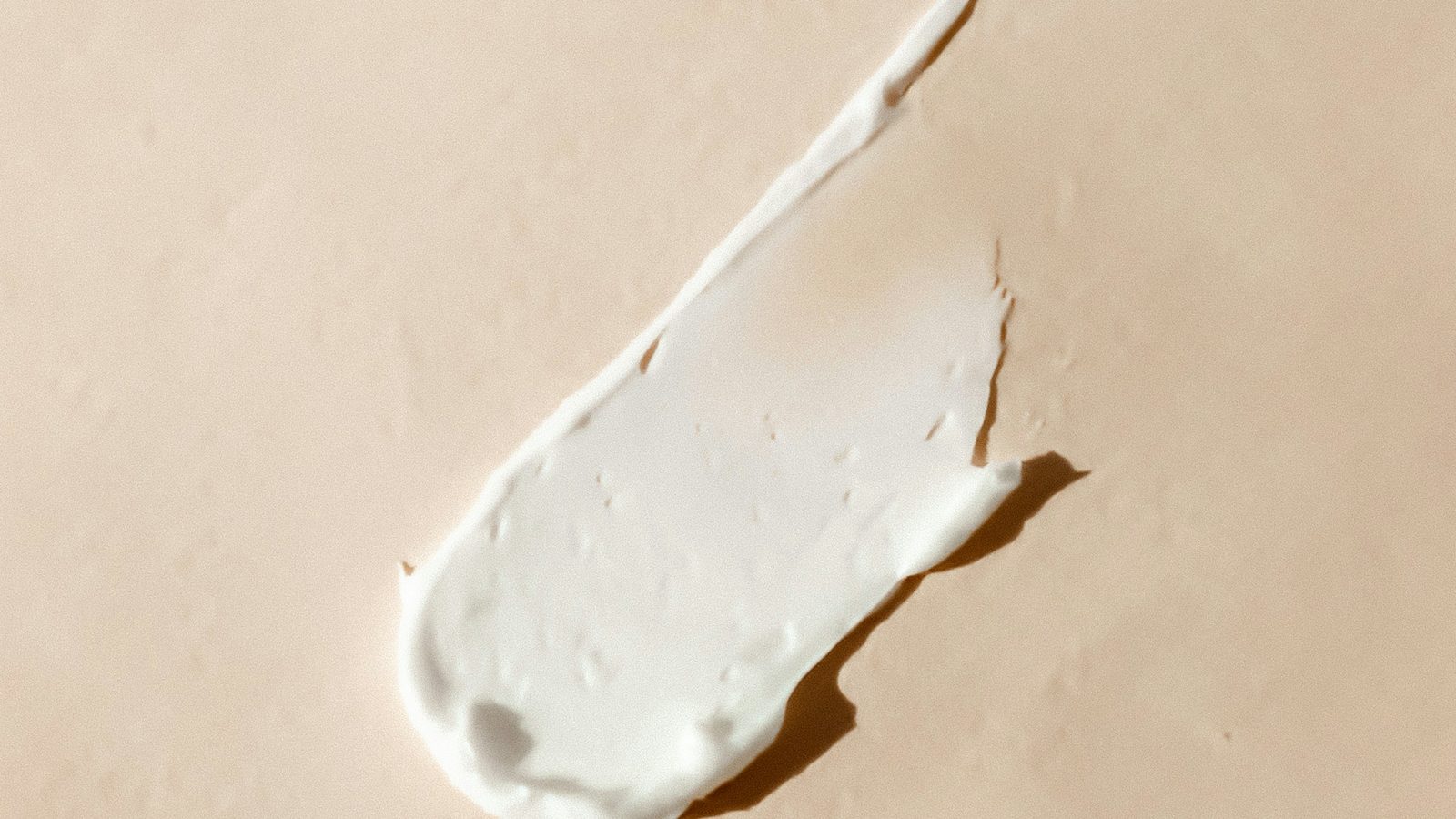 En klat hvid creme på en beige overflade